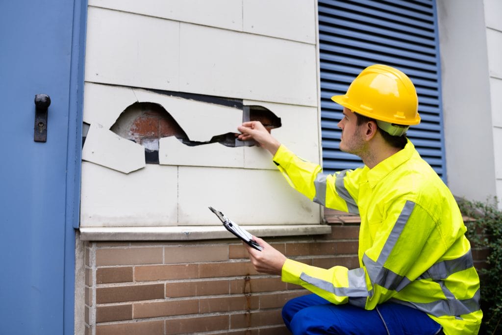 An Expert Discovering Damage On The Exterior Of A Building